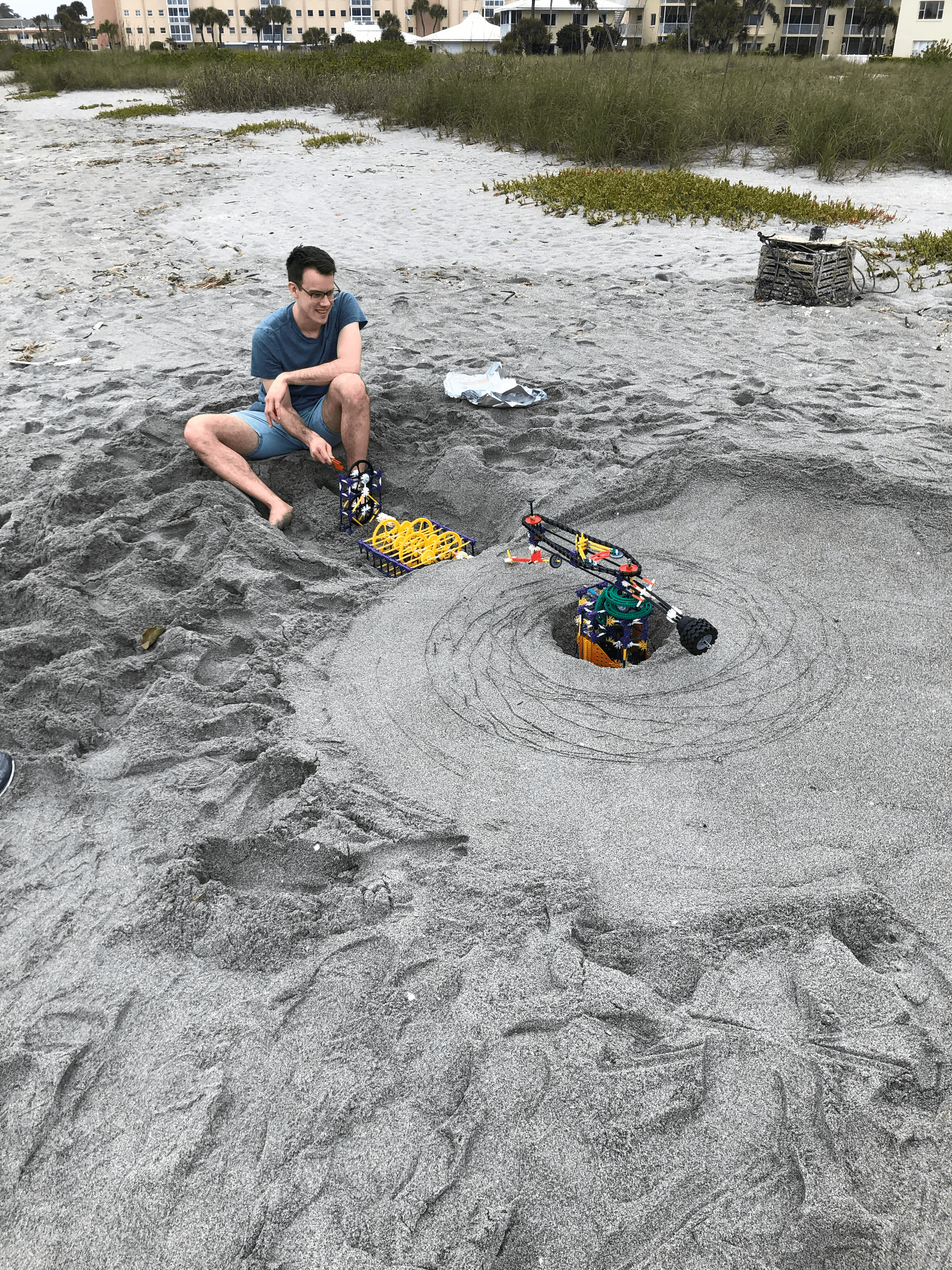 Person cranking the K'nex spirograph mechanism on the beach
